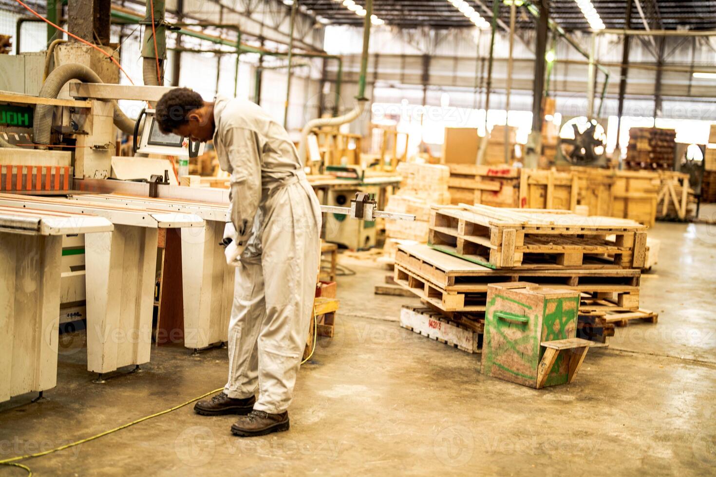 African man workers engineering standing with confidence with working suite dress and hand glove in front machine. Concept of smart industry worker operating. Wood factory produce wood palate. photo