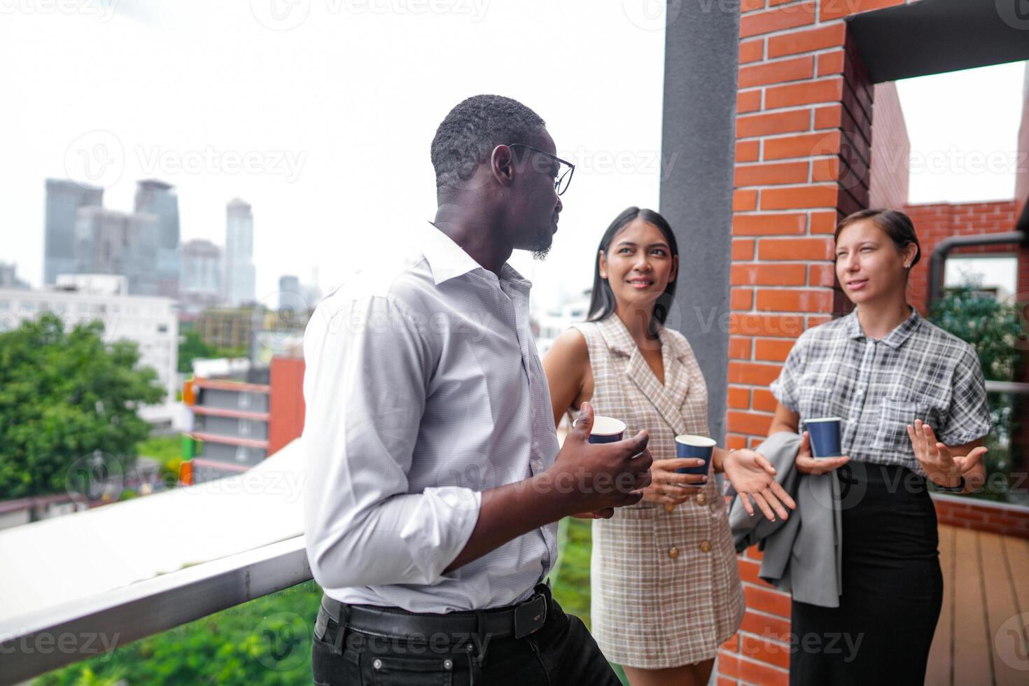 equipo de negocio personas inteligente hombre y mujer estar a al aire libre terraza edificio y hablar juntos con desayuno comida y café en el mano en bueno sensación con ciudad espacio edificio. negocio Mañana. foto