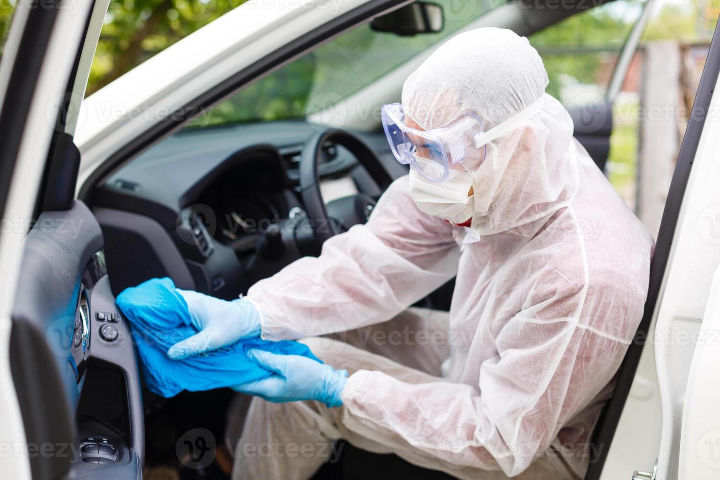 Disinfectant worker character in protective mask and suit sprays bacterial or virus in a car. photo