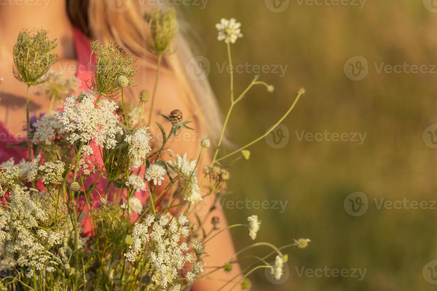 Woman holding bouquet of flowers and enjoys in the nature.Focus on flowers. photo