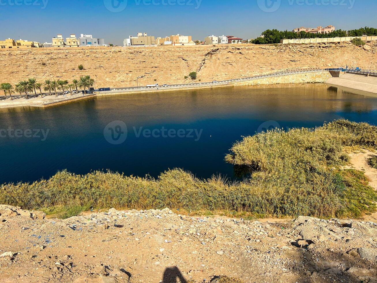 A beautiful daytime view of Wadi Namar Dam in riyadh , Saudi Arabia. The water of the dam and the surrounding hills are presenting a beautiful scene in the sunlight. photo