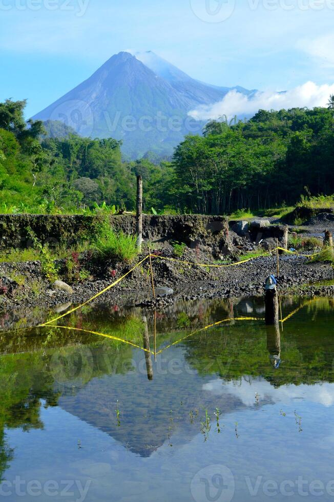 Merapi volcano with its reflection from small puddle photo