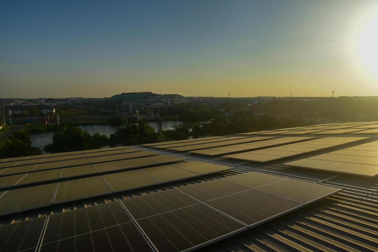 imagen de un solar panel campo en techo de un industrial fábrica en el noche ese es usado a Produce eléctrico energía. eso usos limpiar energía. allí es No contaminación y ayuda reducir producción costos foto