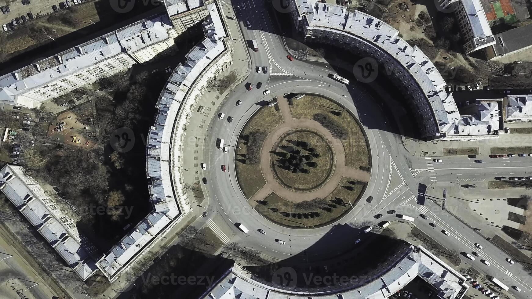 Top view of roundabout in city center. Roundabout with busy traffic of cars, surrounded by houses in city center on sunny day photo