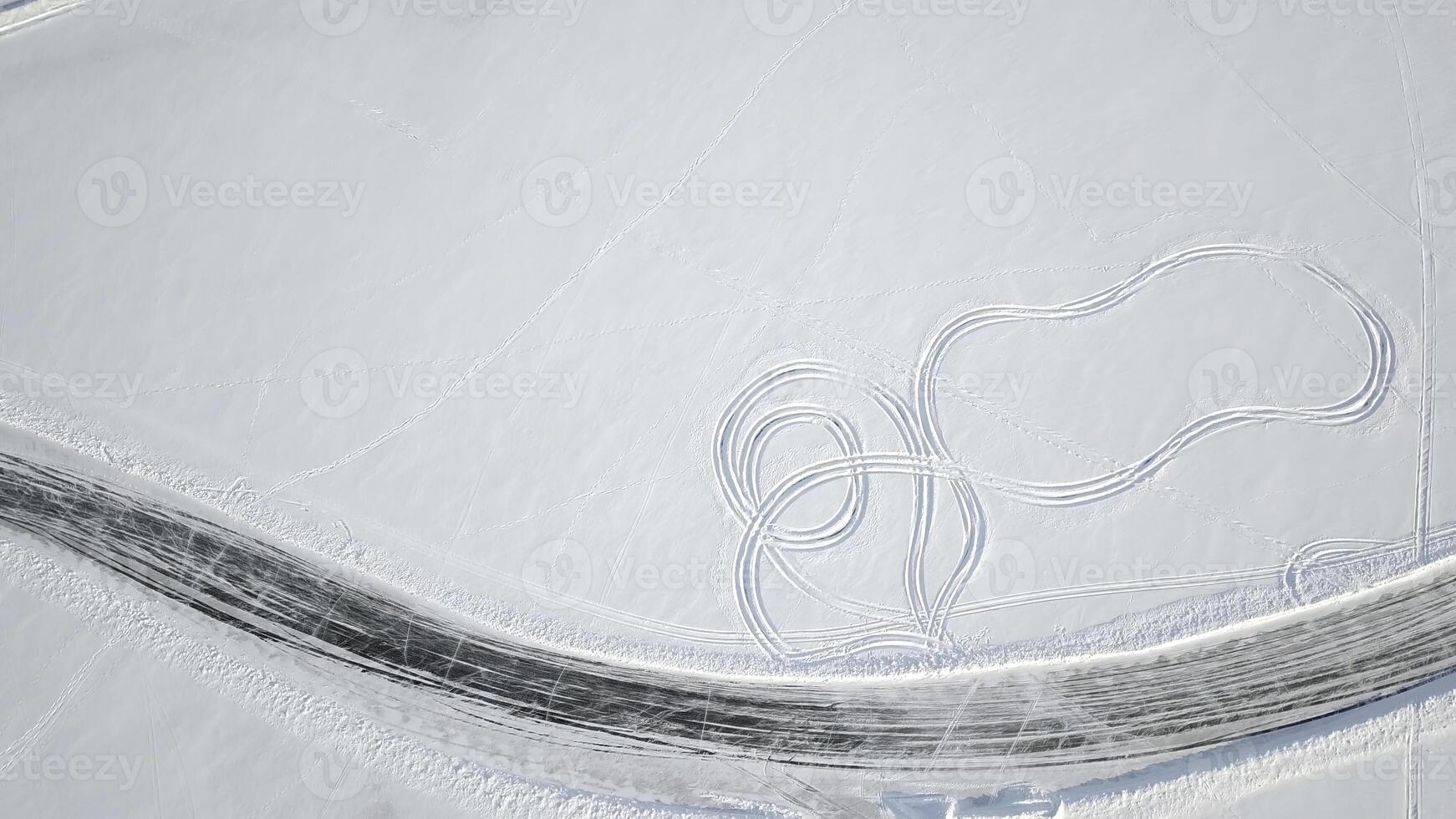 Aerial view on driving car at snowy track. One car driving through the winter forest on country road. Top view from drone photo