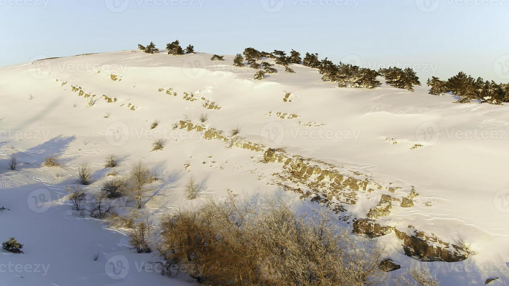 Winter Landscape with Stone Rock Covered with Snow. Shot. Top view of the snow-covered hill in the forest photo