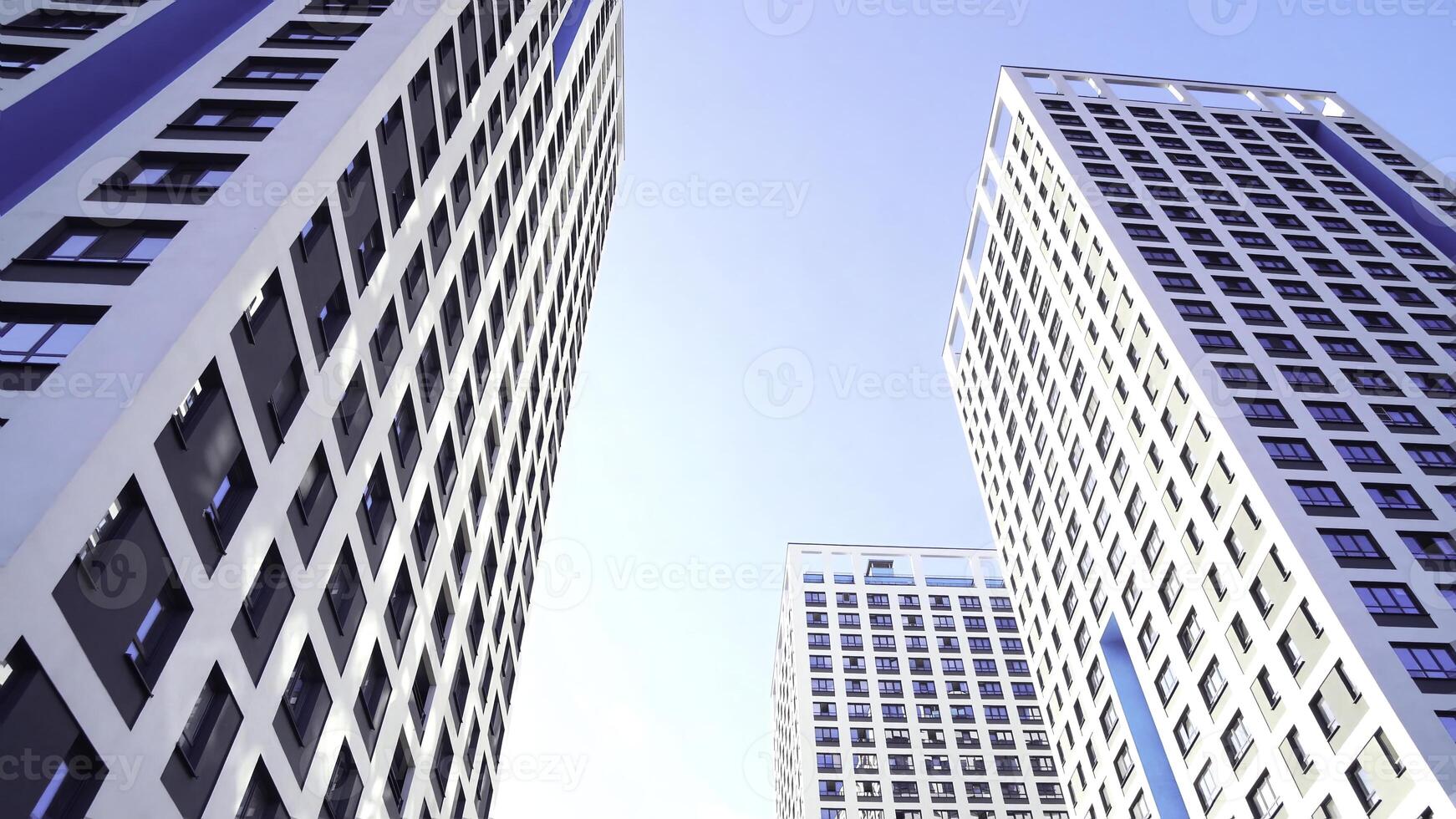 Bottom view of new residential high-rise buildings with blue sky. Urban environment. Frame. Newest residential complexes with an eco-friendly environment photo