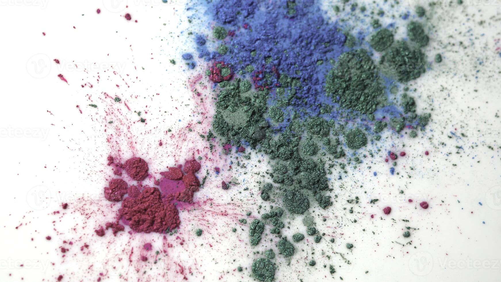 Top view of dry colorful inks falling in white liquid substance. Beautiful iridescent background of green, blue and rose powder in white fluid. photo