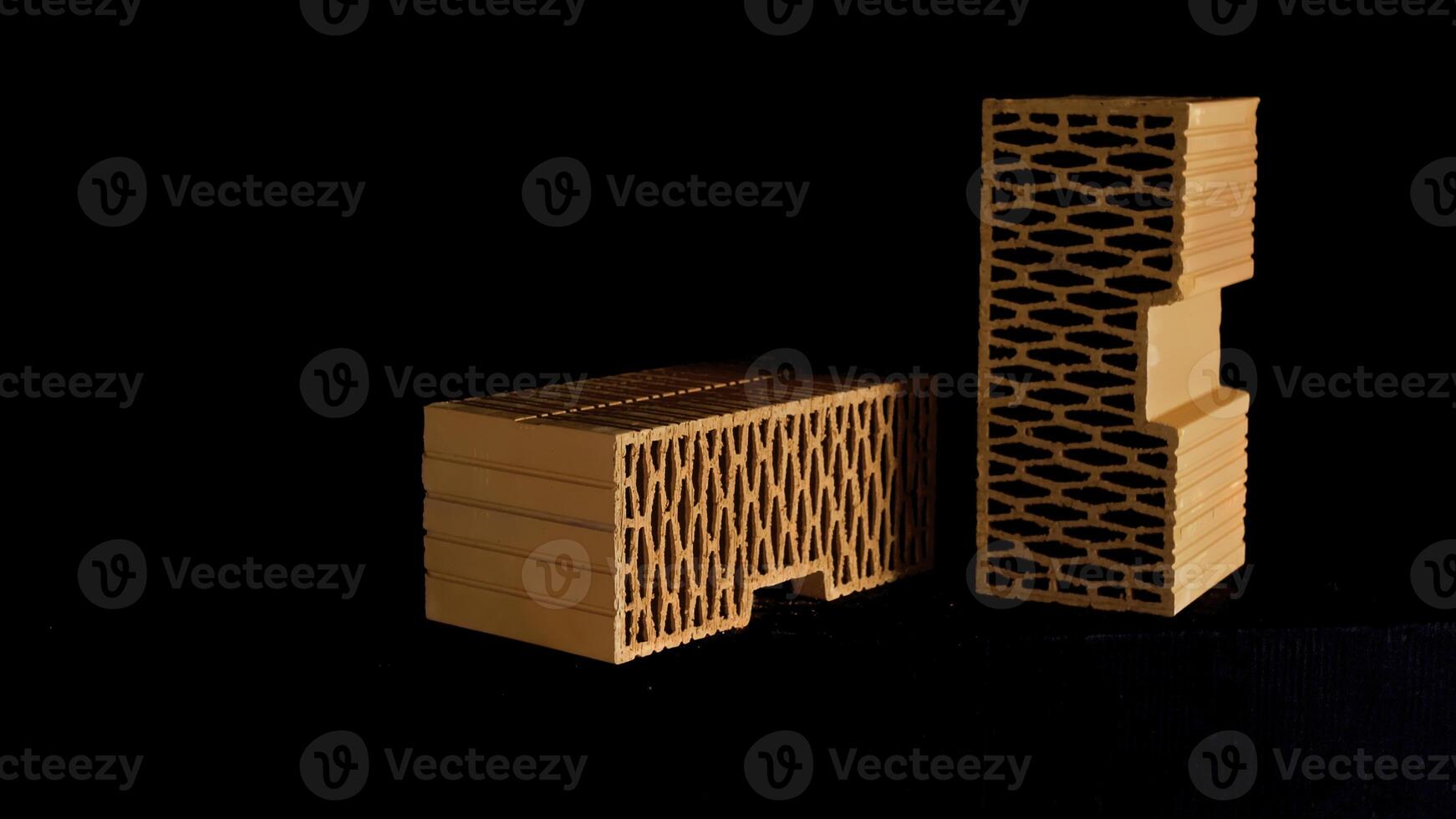 Close up of orange perforated bricks with round holes moving isolated on black background. Stock footage. Materials for the building of new brick house. photo