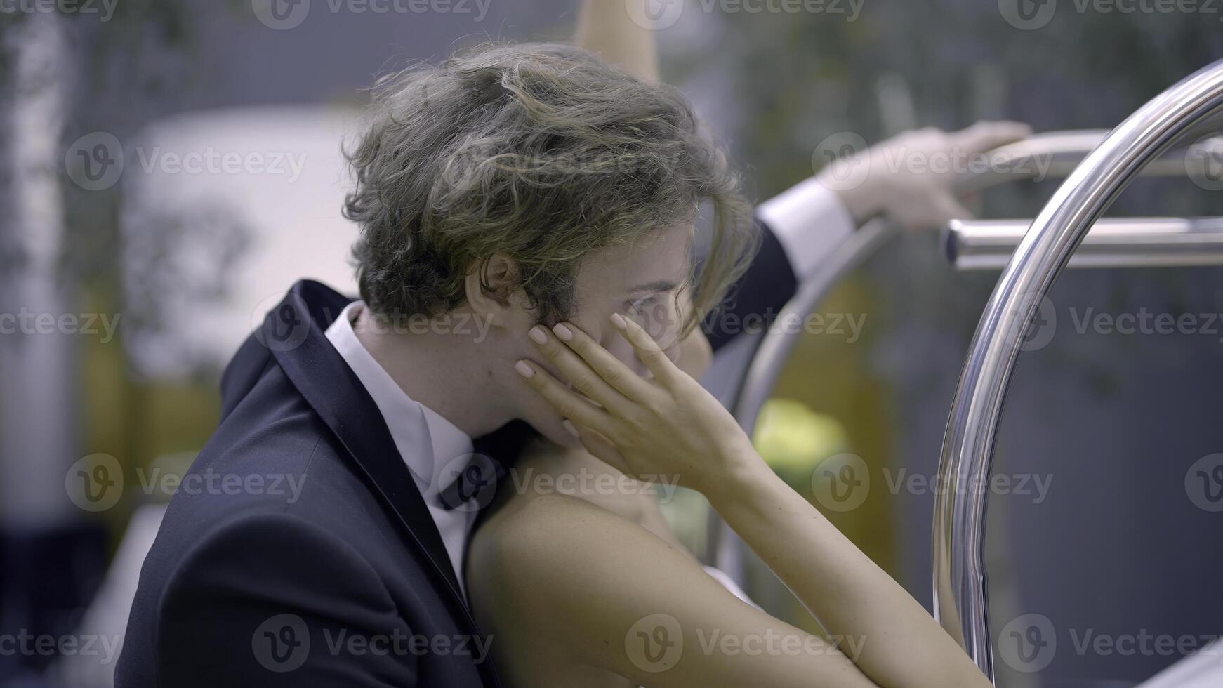 Stylish happy wedding couple softly hugging indoors during photosession. Action. Side view of romantic newlywed groom and bride. photo