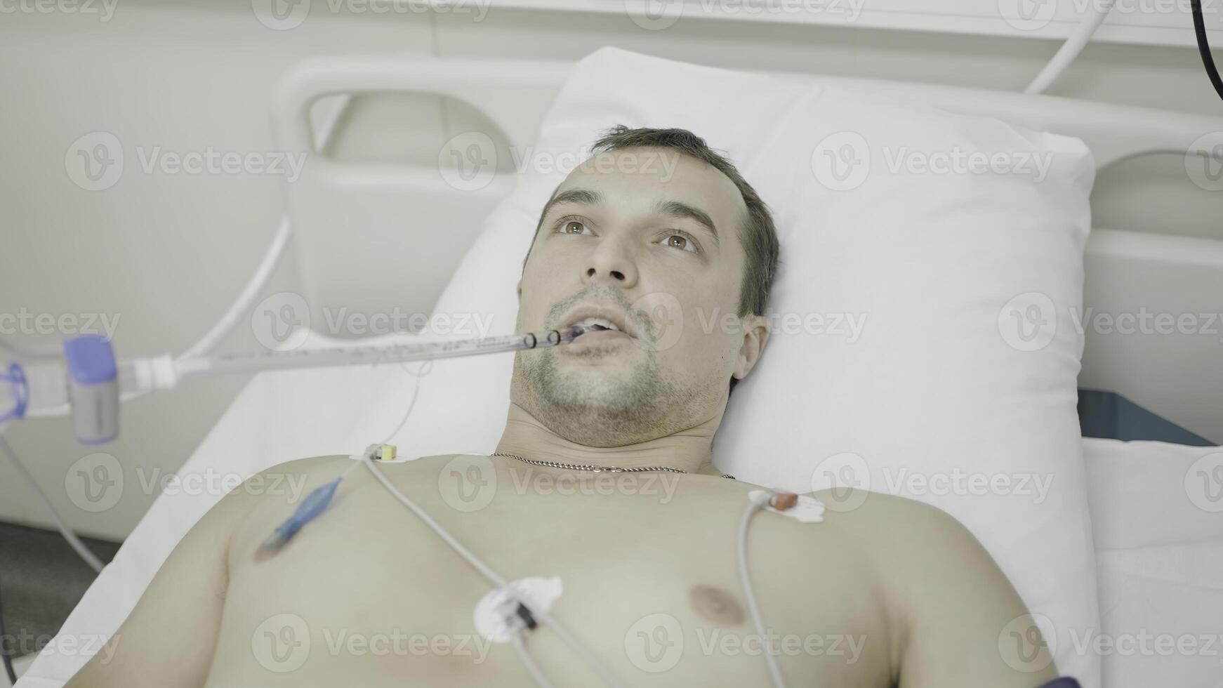 en el operando habitación. acción. un hombre acostado en un hospital quien es mirando a un radiografía de un latido del corazón y quien estaba respiración mediante un especial tubo. foto