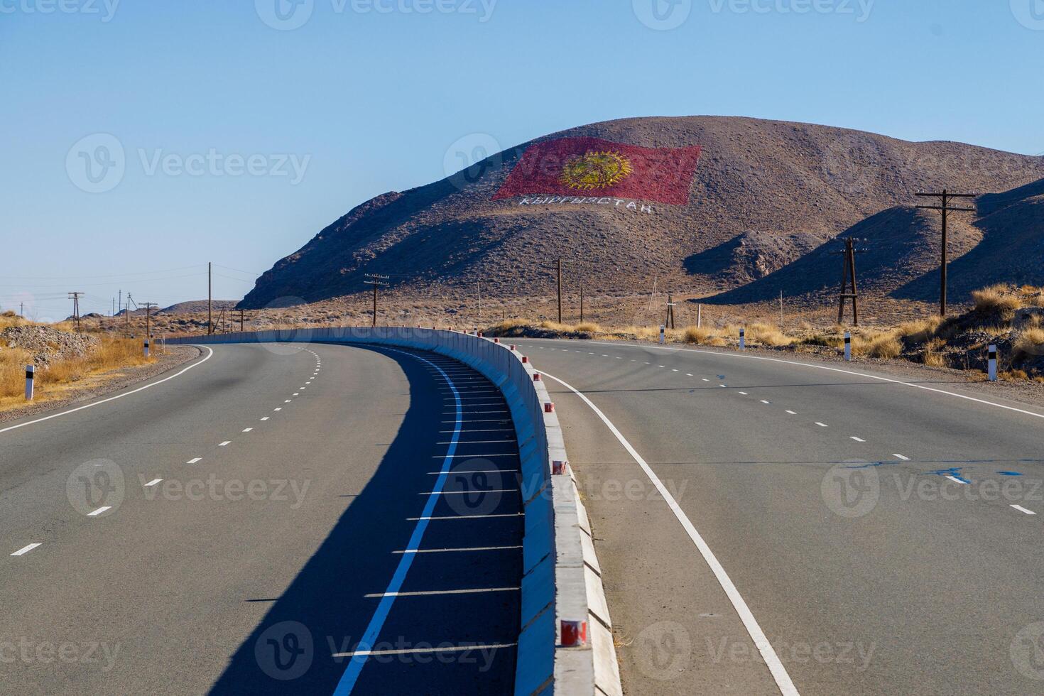 The flag of Kyrgyzstan is drawn on a mountain at sunny autumn day, showcasing the nation's pride and spirit. photo