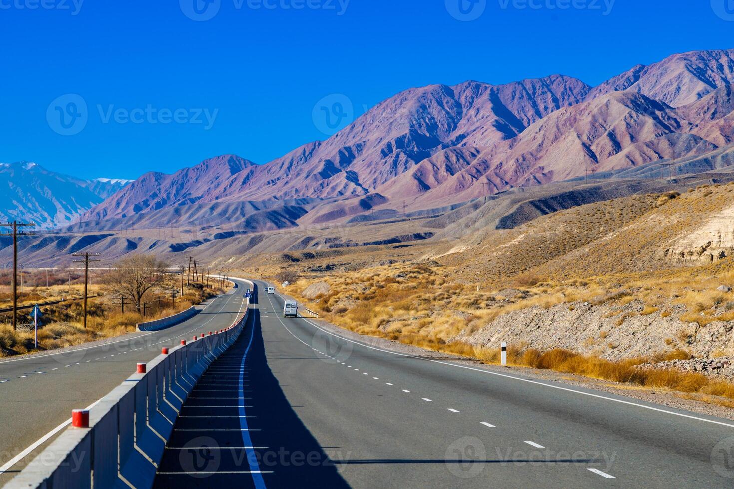 highway road with separating concrete barrier in mountains at sunny autumn day photo