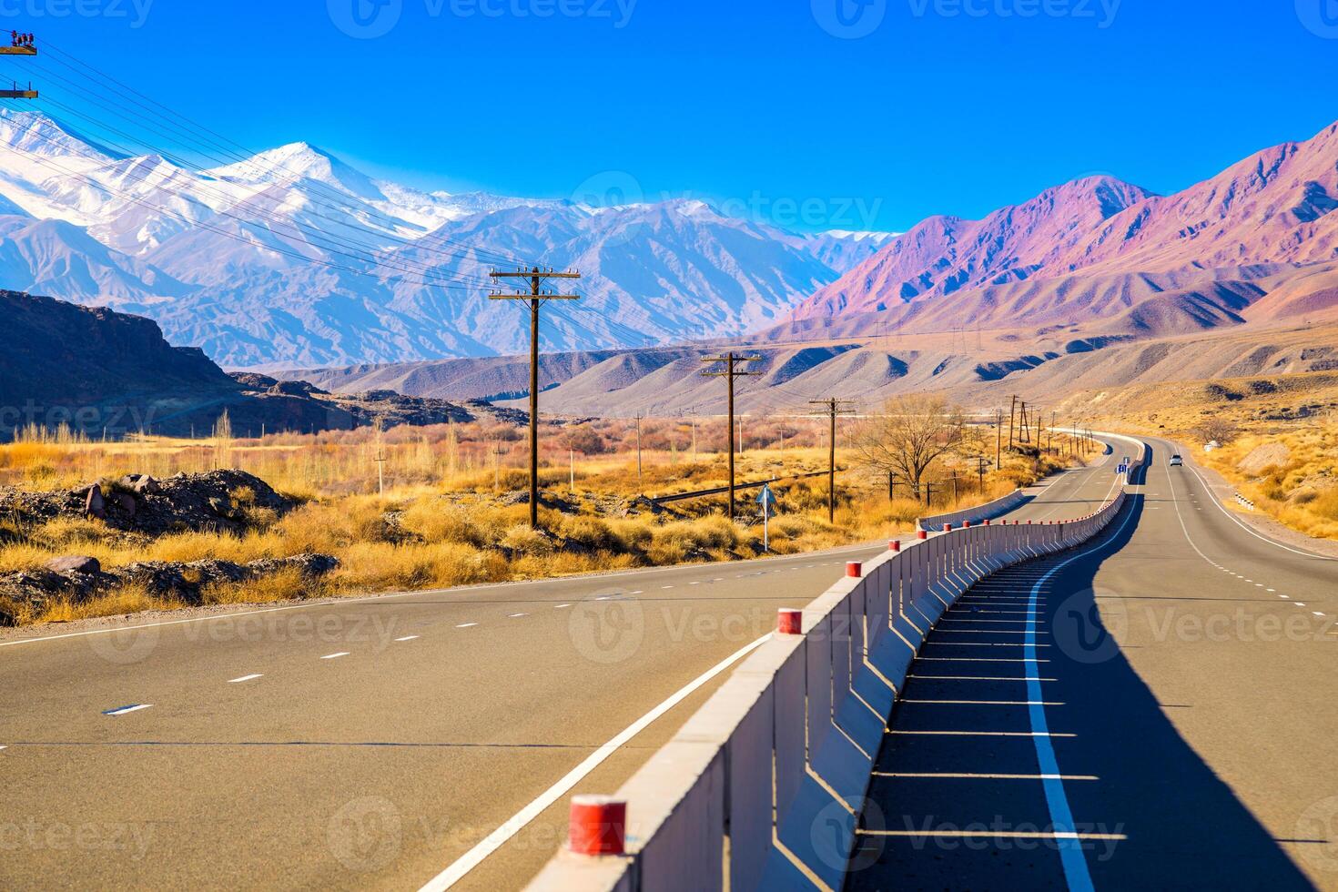 highway road with separating concrete barrier in mountains at sunny autumn day photo