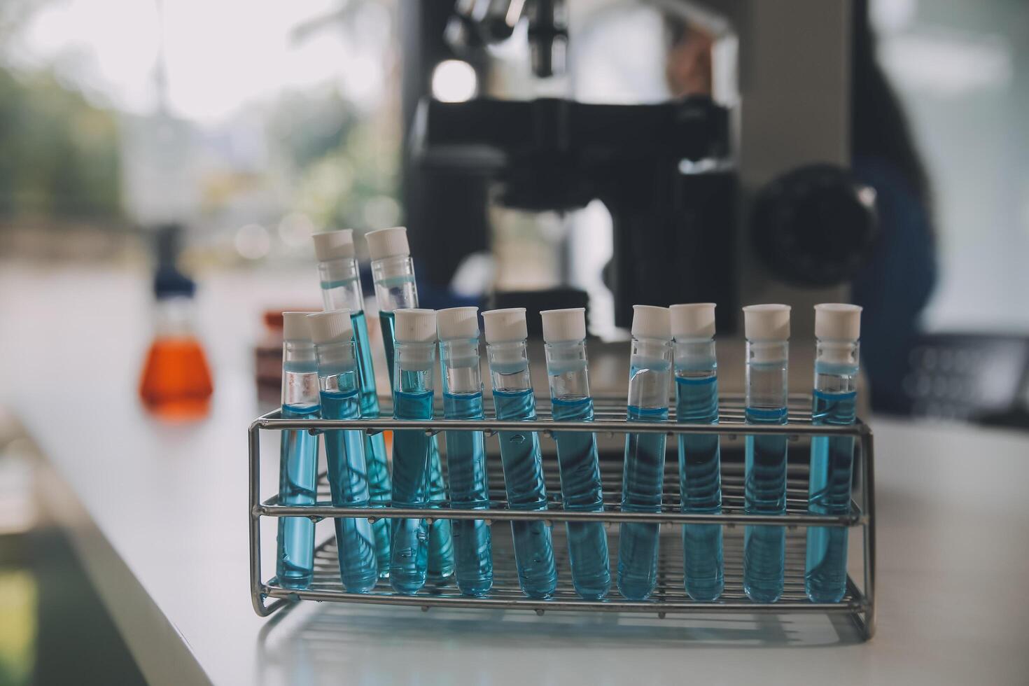 biochemical research scientist team working with microscope for coronavirus vaccine development in pharmaceutical research labolatory, selective focus photo