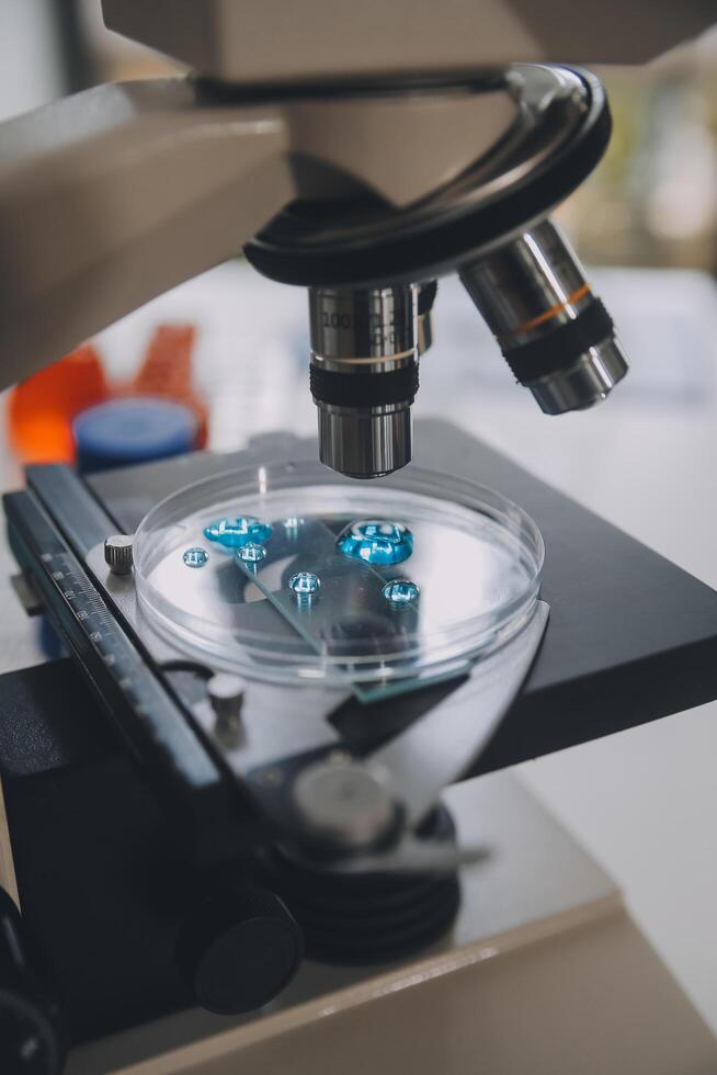 equipo científico de investigación bioquímica que trabaja con microscopio para el desarrollo de vacunas contra el coronavirus en laboratorios de investigación farmacéutica, enfoque selectivo foto