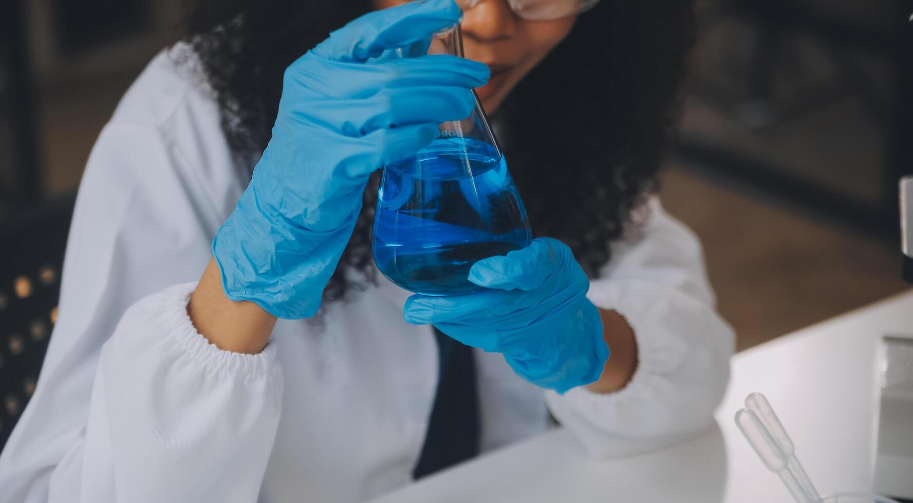 equipo científico de investigación bioquímica que trabaja con microscopio para el desarrollo de vacunas contra el coronavirus en laboratorios de investigación farmacéutica, enfoque selectivo foto