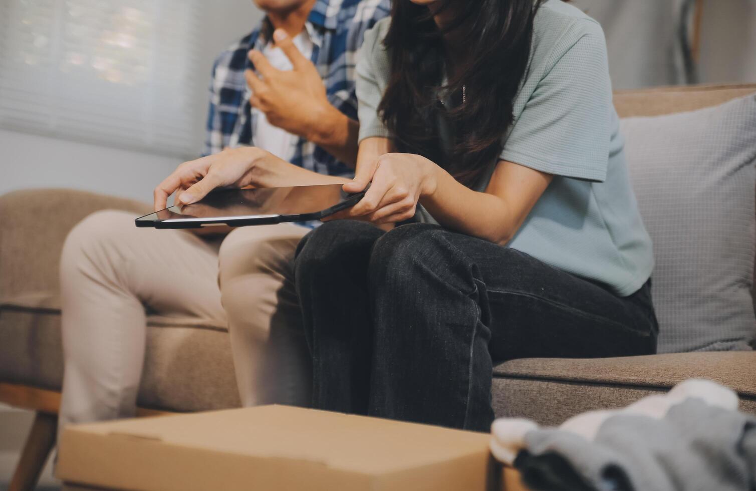 Two Asian blogger showing clothes in front of the camera to recording vlog video live streaming at her shop. Online Shopping Cart notion. on sofa at home photo