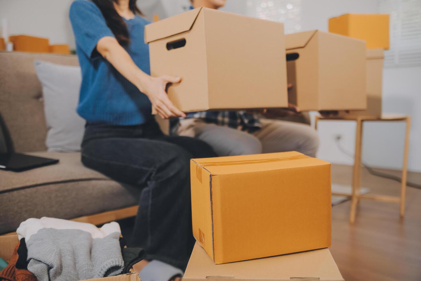 Two Asian blogger showing clothes in front of the camera to recording vlog video live streaming at her shop. Online Shopping Cart notion. on sofa at home photo