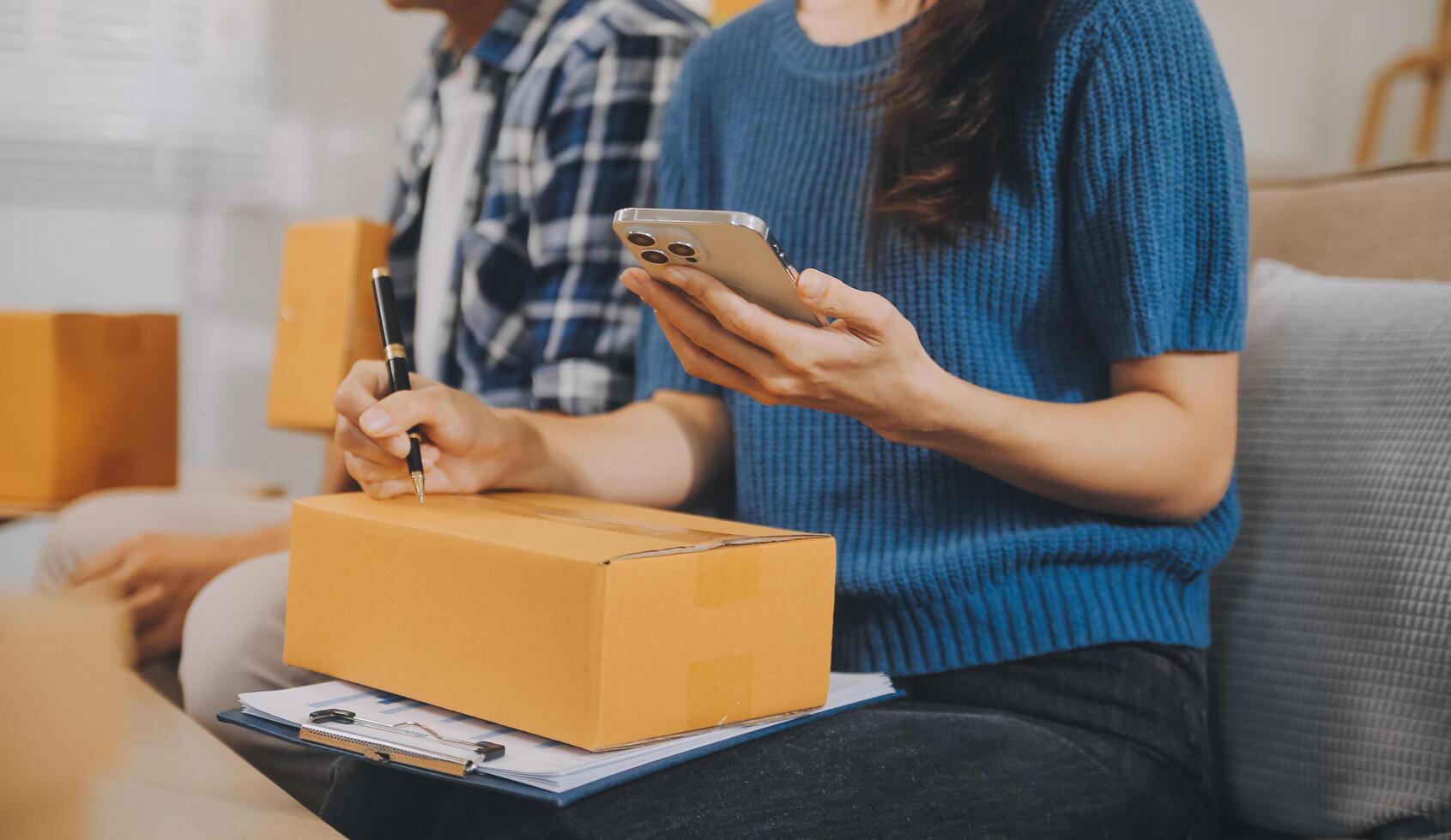 Two Asian blogger showing clothes in front of the camera to recording vlog video live streaming at her shop. Online Shopping Cart notion. on sofa at home photo