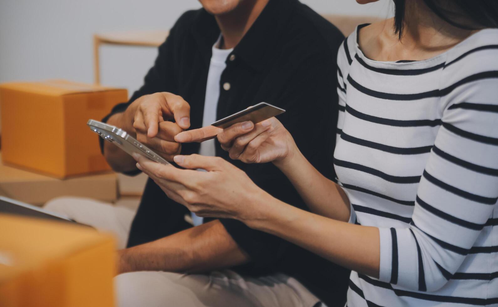 Two Asian blogger showing clothes in front of the camera to recording vlog video live streaming at her shop. Online Shopping Cart notion. on sofa at home photo
