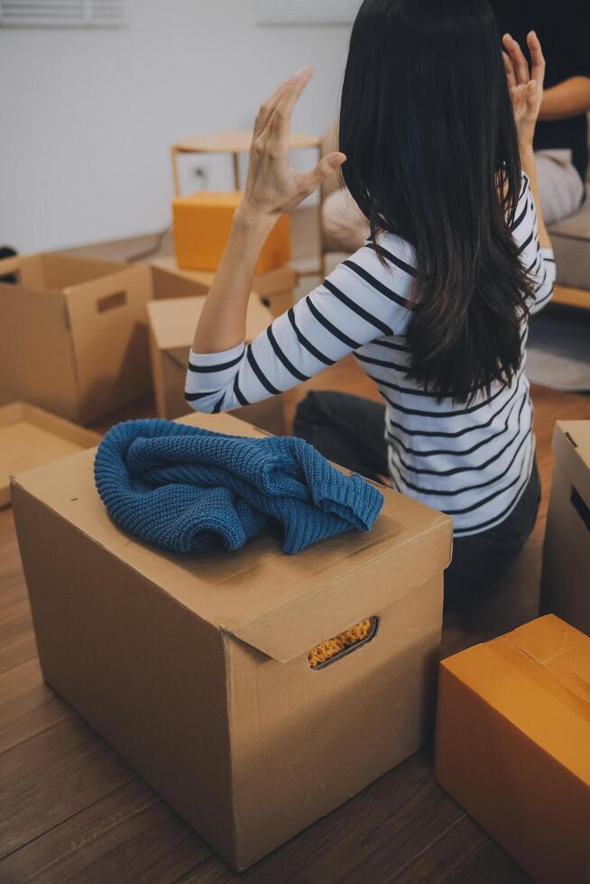 Two Asian blogger showing clothes in front of the camera to recording vlog video live streaming at her shop. Online Shopping Cart notion. on sofa at home photo