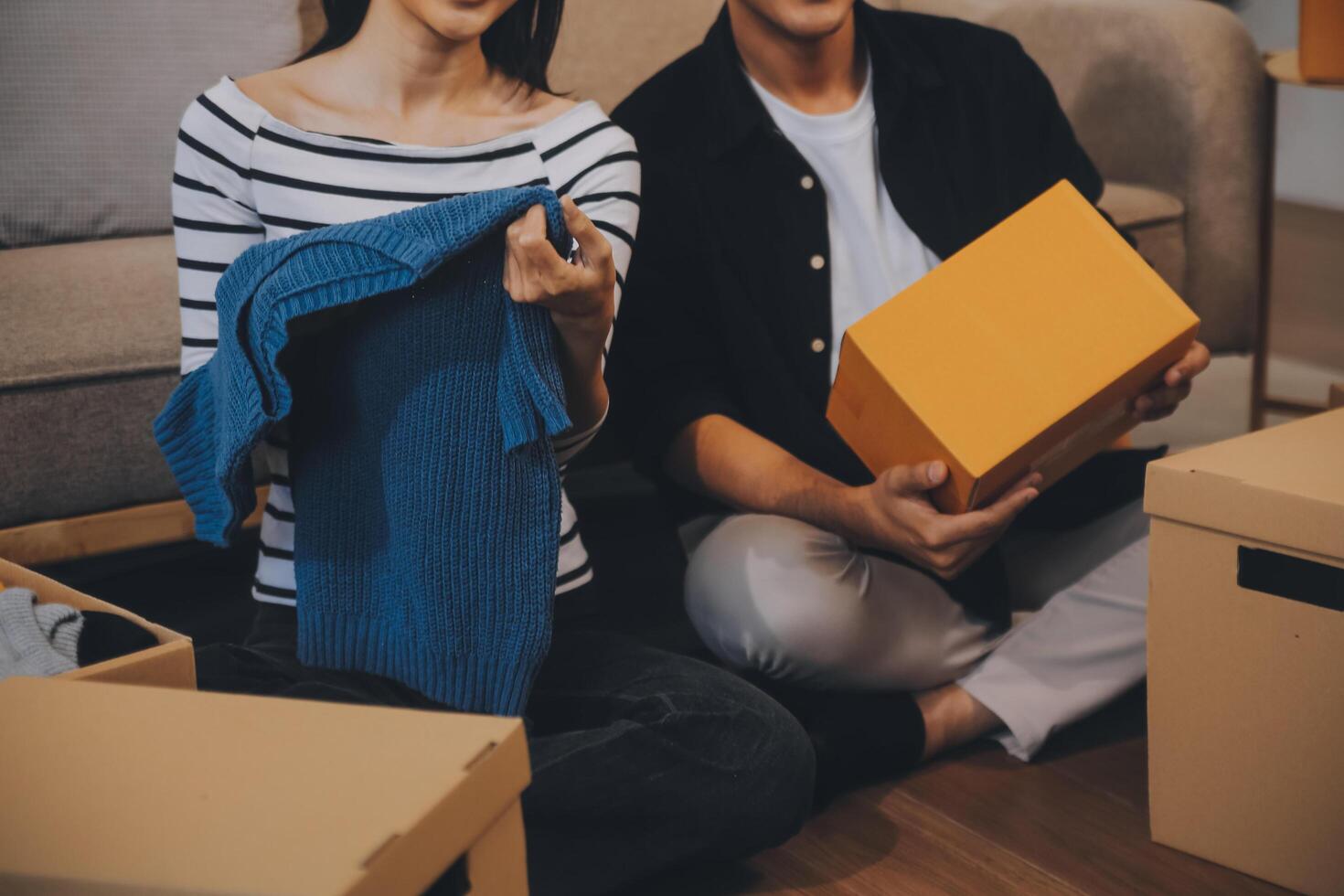 Two Asian blogger showing clothes in front of the camera to recording vlog video live streaming at her shop. Online Shopping Cart notion. on sofa at home photo