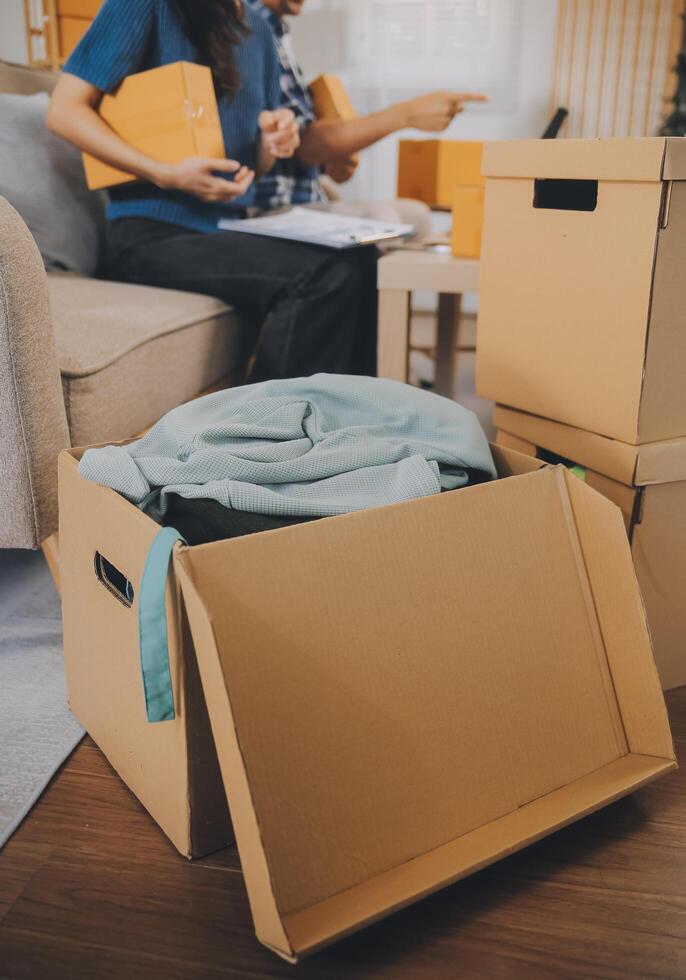 Two Asian blogger showing clothes in front of the camera to recording vlog video live streaming at her shop. Online Shopping Cart notion. on sofa at home photo