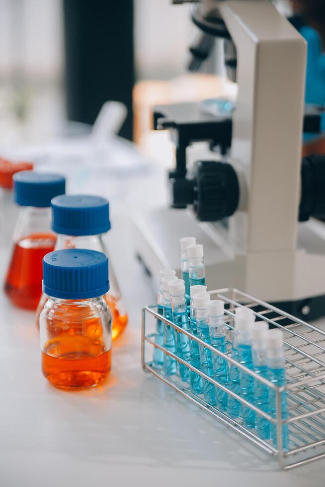 biochemical research scientist team working with microscope for coronavirus vaccine development in pharmaceutical research labolatory, selective focus photo