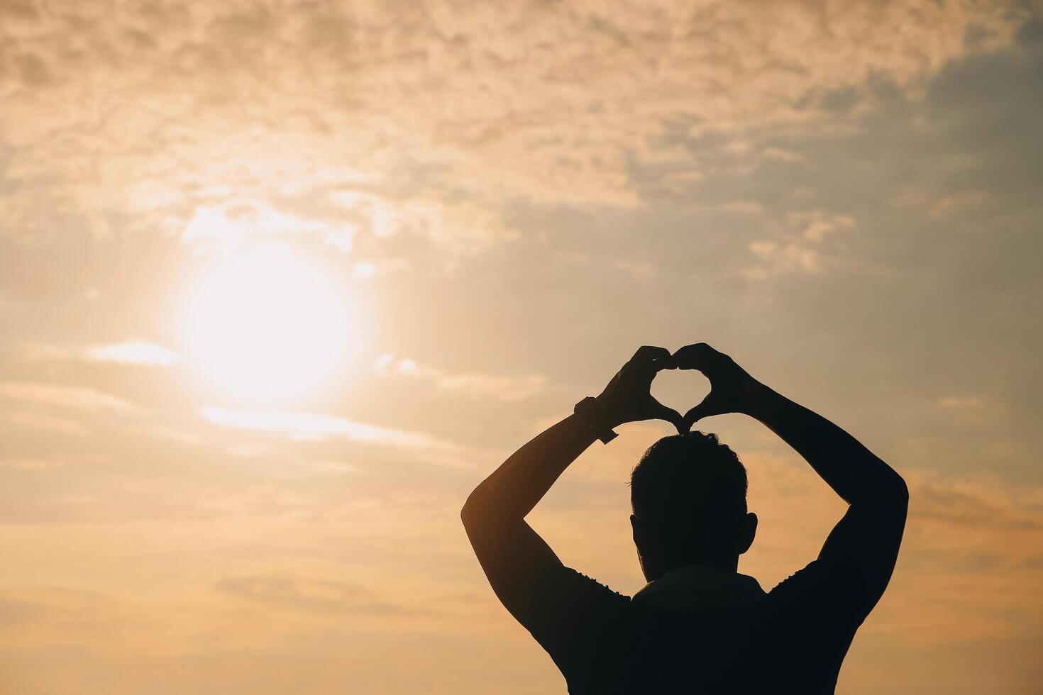 Hand heart frame shape silhouette made against the sun sky of a sunrise or sunset on photo