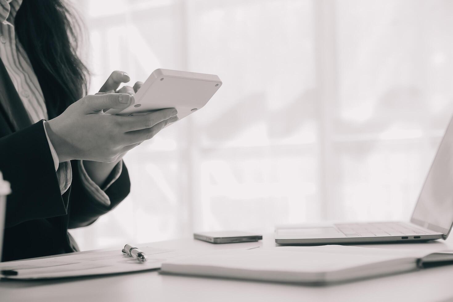 Businessman using a calculator to calculate numbers on a company's financial documents, he is analyzing historical financial data to plan how to grow the company. Financial concept. photo
