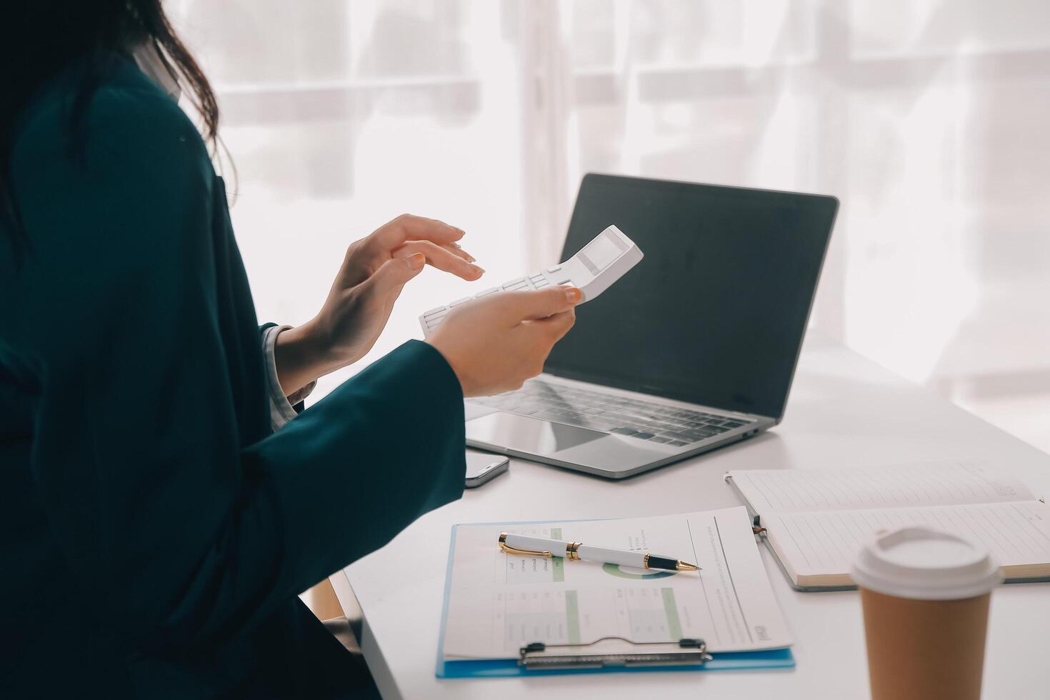Businessman using a calculator to calculate numbers on a company's financial documents, he is analyzing historical financial data to plan how to grow the company. Financial concept. photo