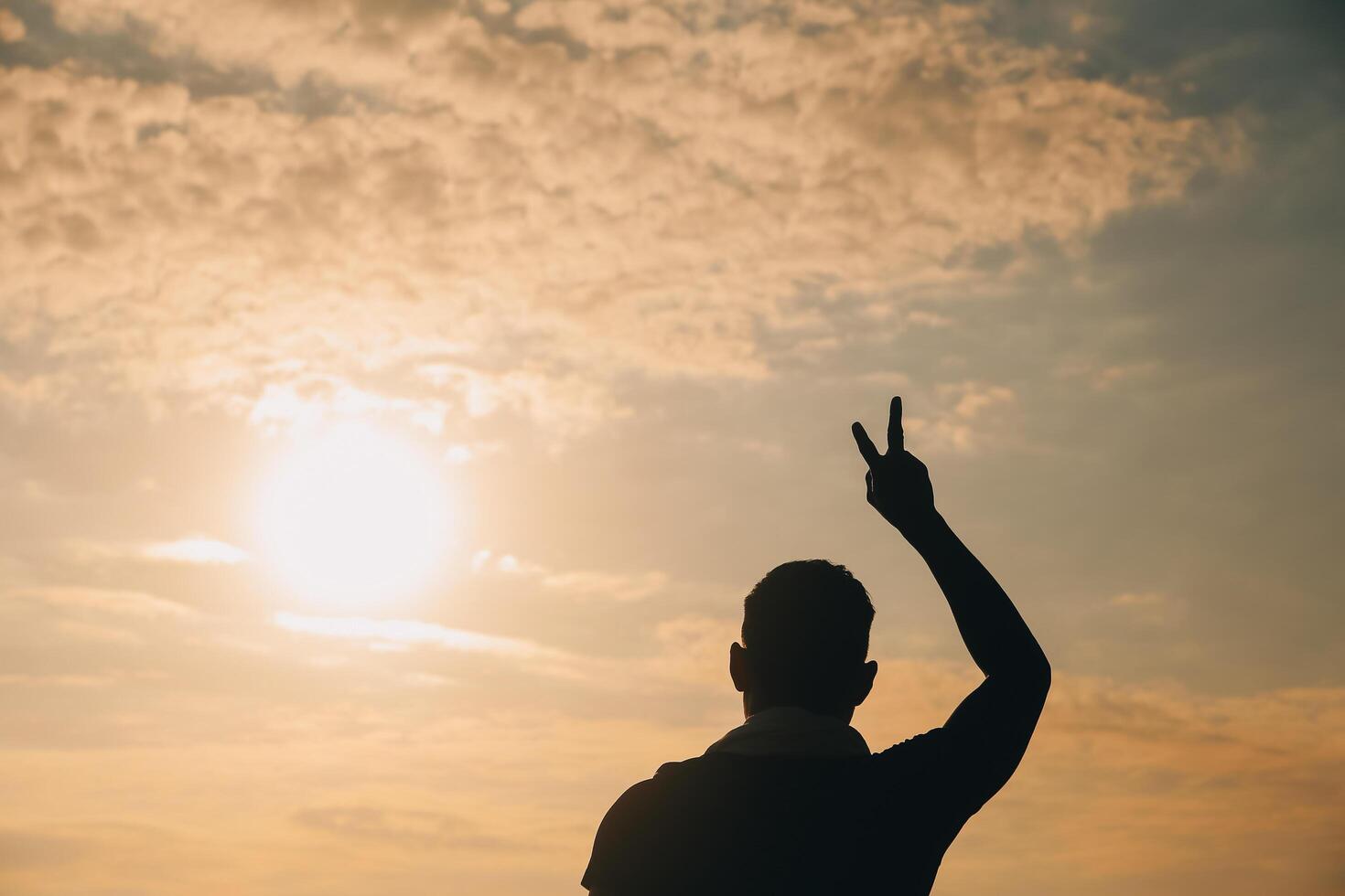 Hand heart frame shape silhouette made against the sun sky of a sunrise or sunset on a mountain. photo