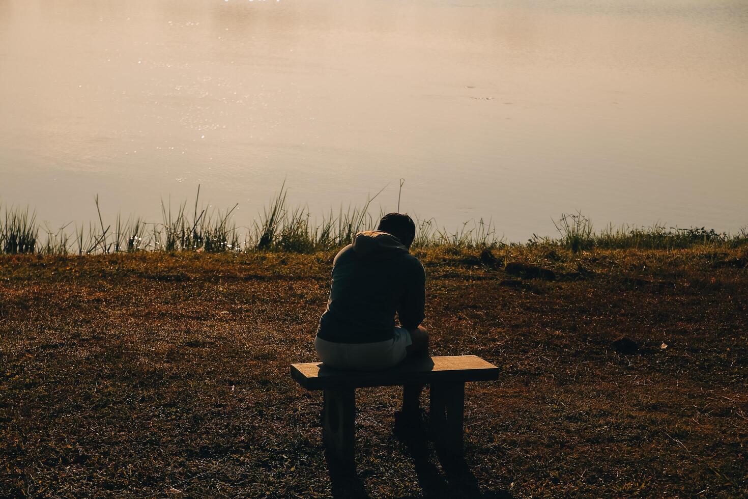 Silhouette of young man sits praying alone at the top of the mountain at sunset with beautiful natural sunlight. photo