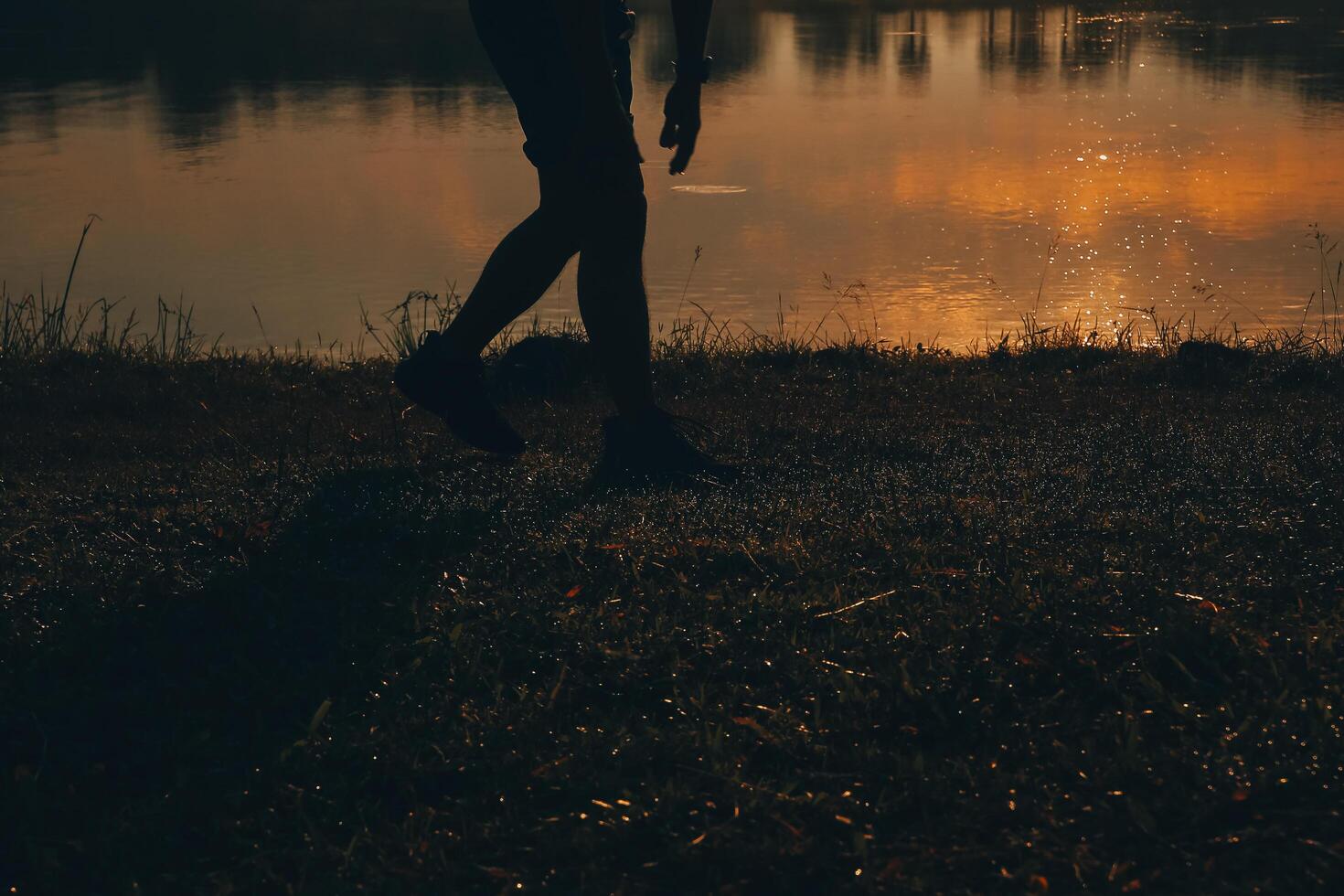 Back view silhouette of a runner man running on the beach at sunset with sun in the background photo