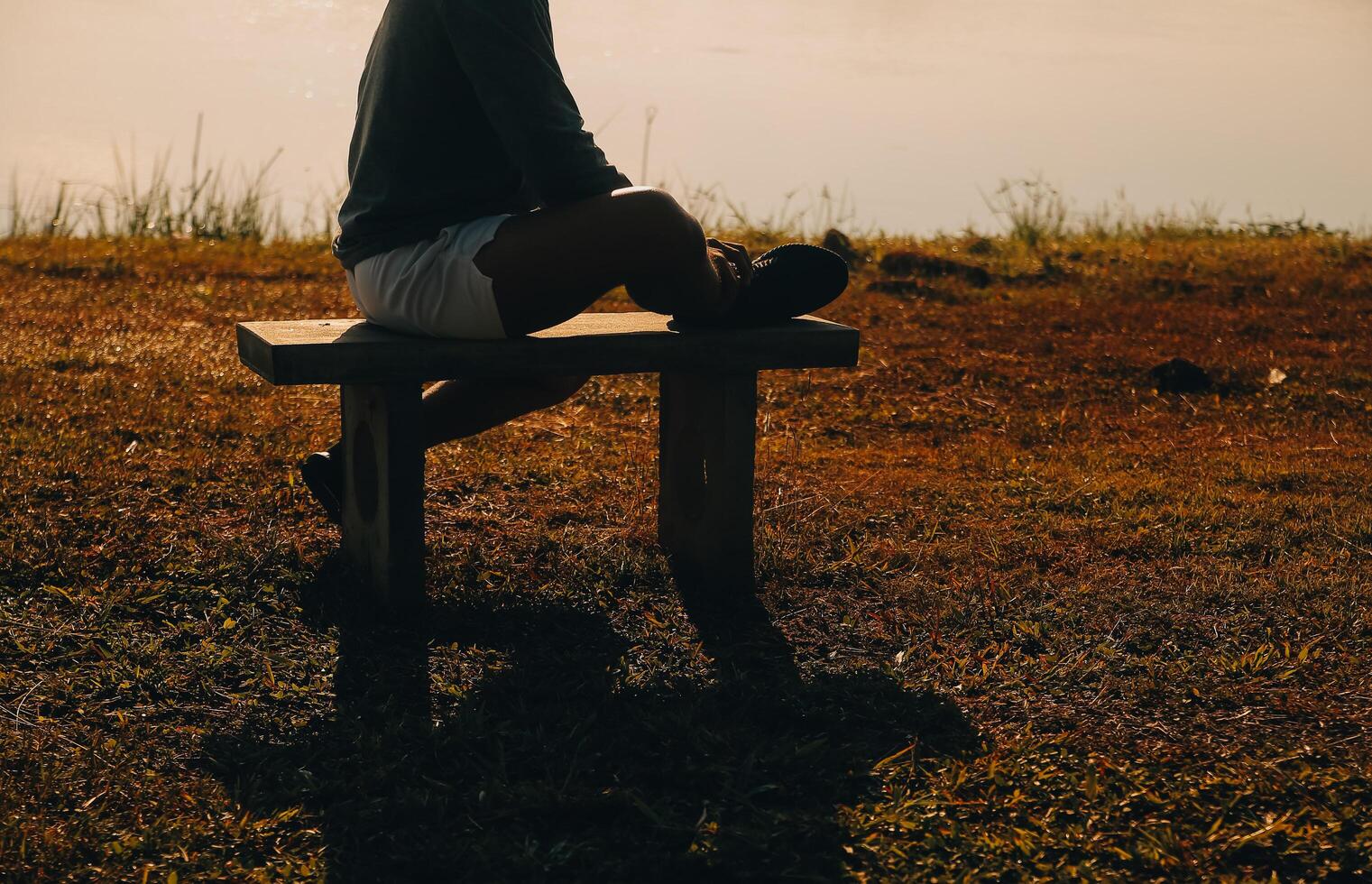 Silhouette of young man sits praying alone at the top of the mountain at sunset with beautiful natural sunlight. photo