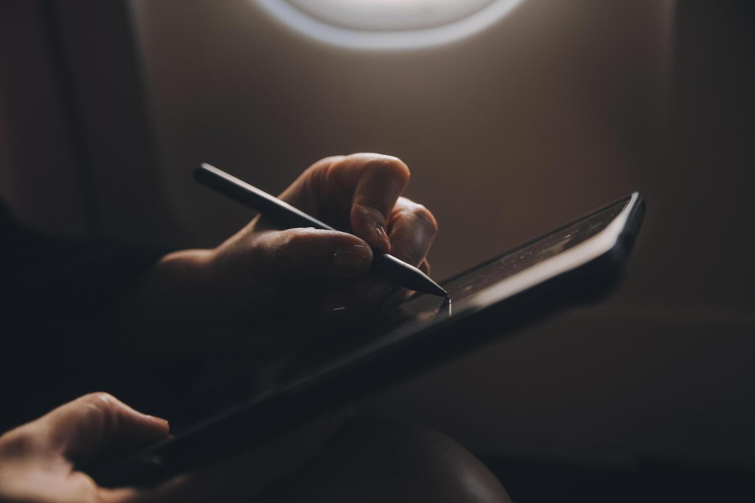 Blonde female tourist checking incoming notification on smartphone sitting on seat of airplane with netbook.Young businesswoman share media from telephone on laptop computer during plane flight photo