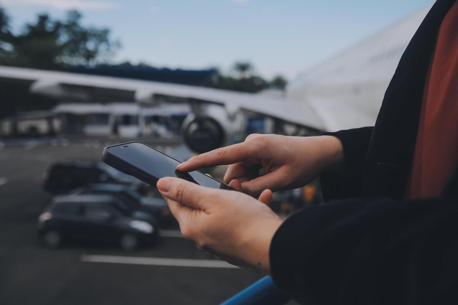 Young asian woman in international airport, using mobile smartphone and checking flight at the flight information board photo