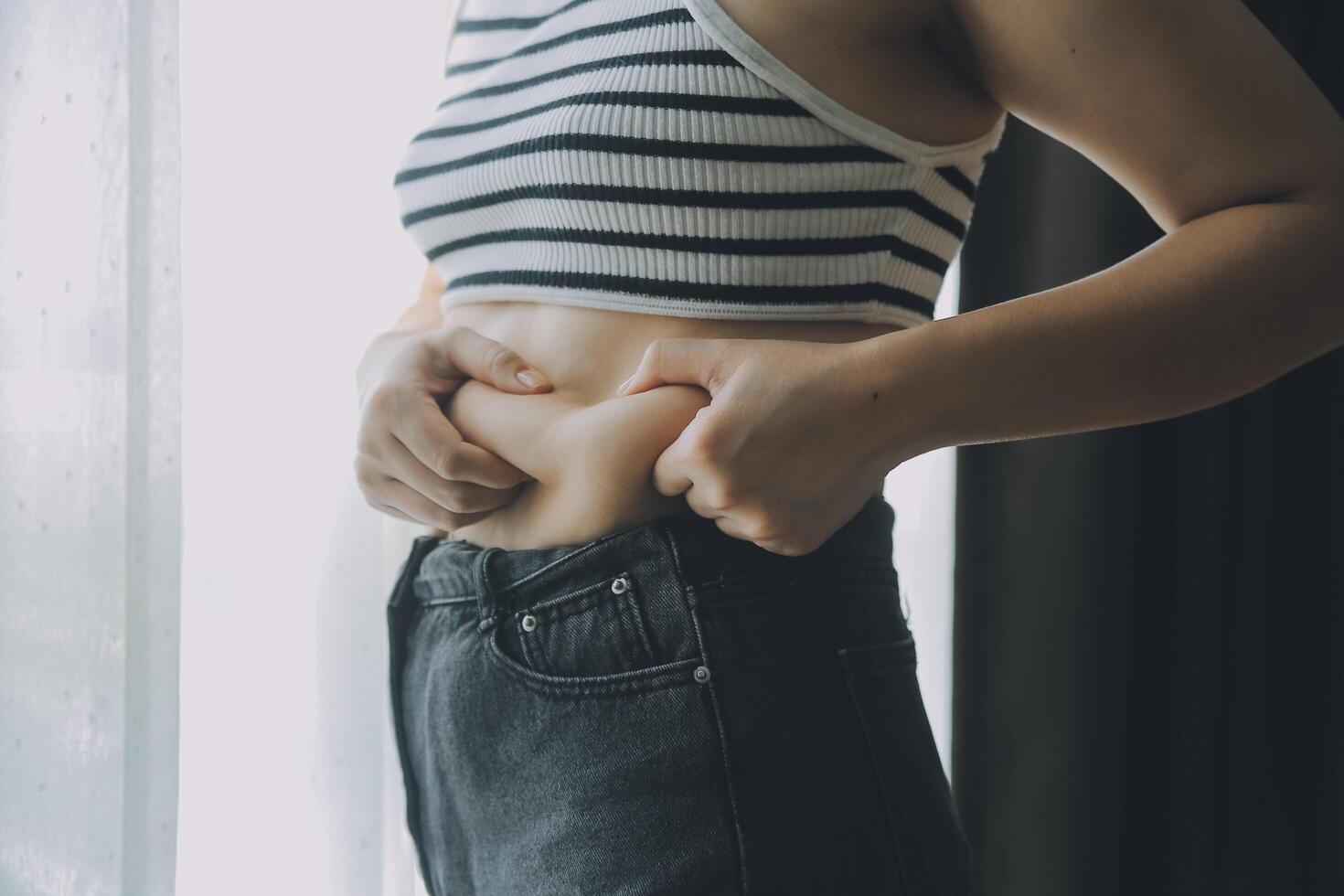 Women body fat belly. Obese woman hand holding excessive belly fat. diet lifestyle concept to reduce belly and shape up healthy stomach muscle. photo