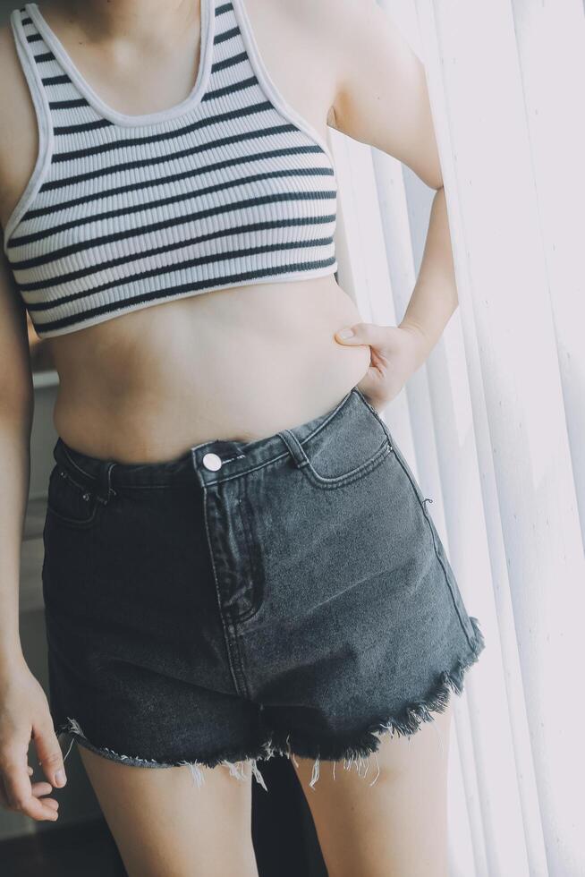 Women body fat belly. Obese woman hand holding excessive belly fat. diet lifestyle concept to reduce belly and shape up healthy stomach muscle. photo
