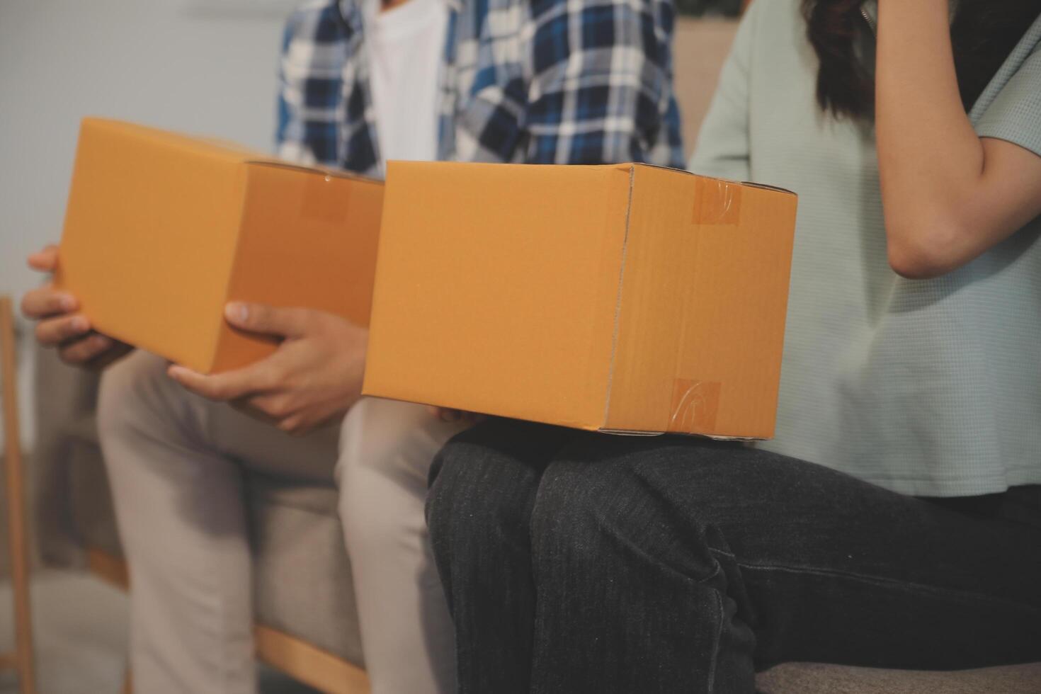 Two Asian blogger showing clothes in front of the camera to recording vlog video live streaming at her shop. Online Shopping Cart notion. on sofa at home photo