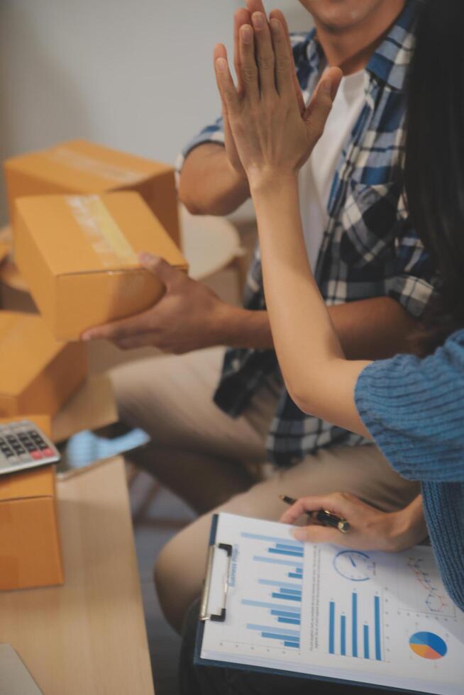 Two Asian blogger showing clothes in front of the camera to recording vlog video live streaming at her shop. Online Shopping Cart notion. on sofa at home photo