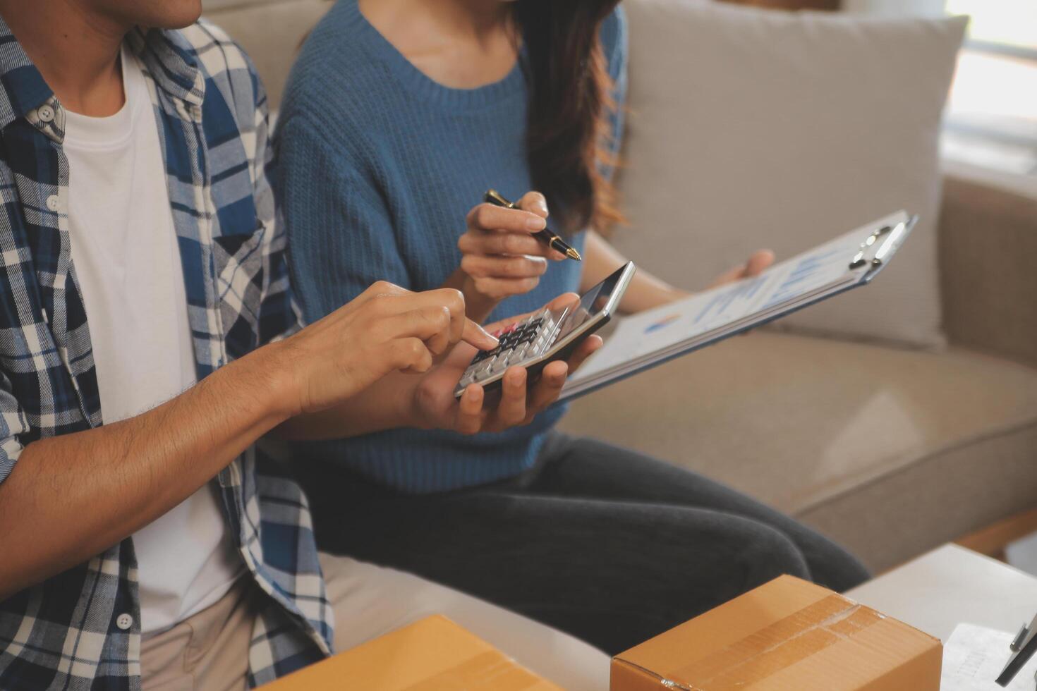 Two Asian blogger showing clothes in front of the camera to recording vlog video live streaming at her shop. Online Shopping Cart notion. on sofa at home photo