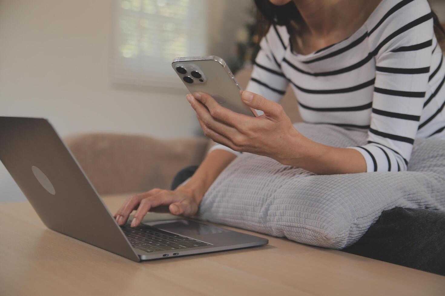 felicidad empresaria hermosa mujer joven asiática de negocios usa un teléfono móvil de uso informal para comprar en línea disfrutar con las redes sociales y una computadora portátil en casa. inicio de una pequeña empresa. banca en línea foto