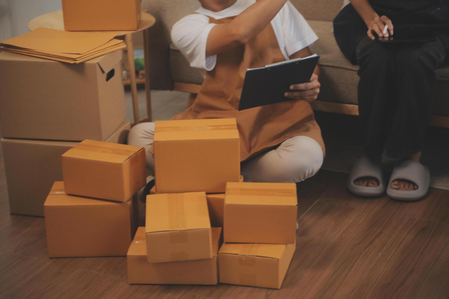 Two Asian blogger showing clothes in front of the camera to recording vlog video live streaming at her shop. Online Shopping Cart notion. on sofa at home photo