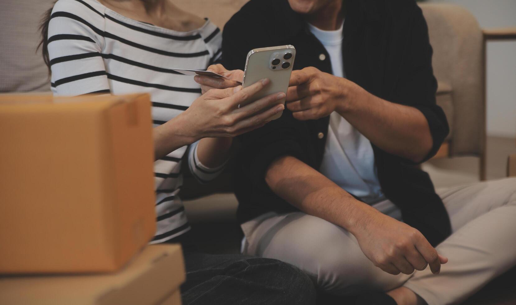 Two Asian blogger showing clothes in front of the camera to recording vlog video live streaming at her shop. Online Shopping Cart notion. on sofa at home photo