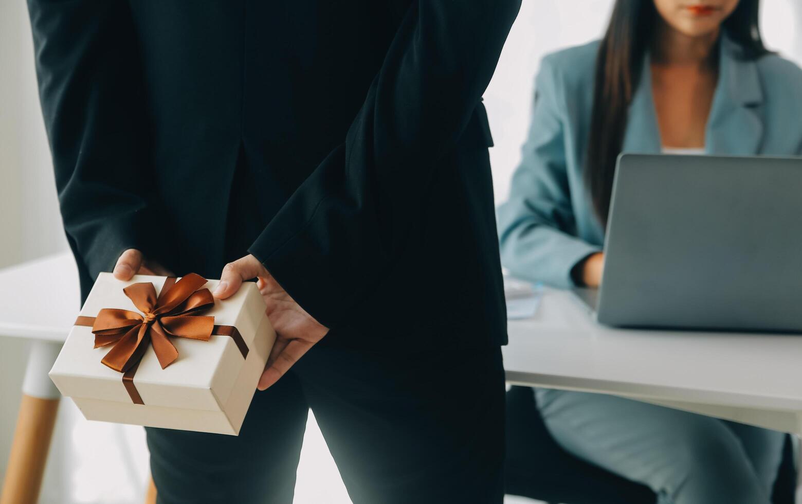 Young businessman giving his colleague present in office. Young man surprise beautiful businesswoman in office. photo