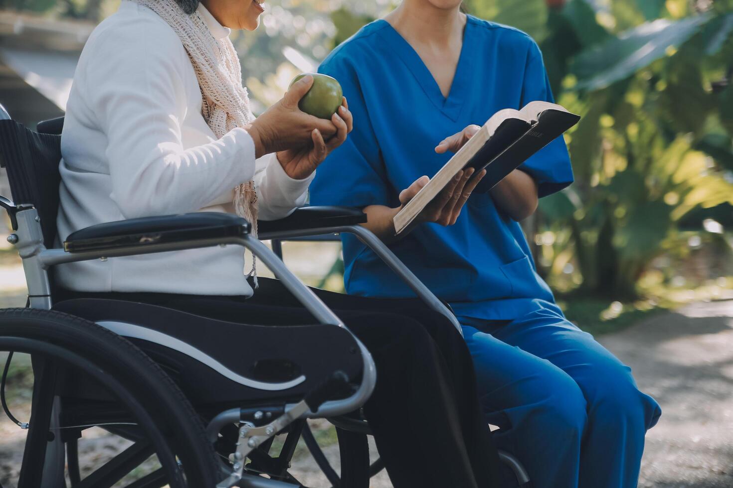 A nurse take care a senior male on wheelchair in his garden at home photo