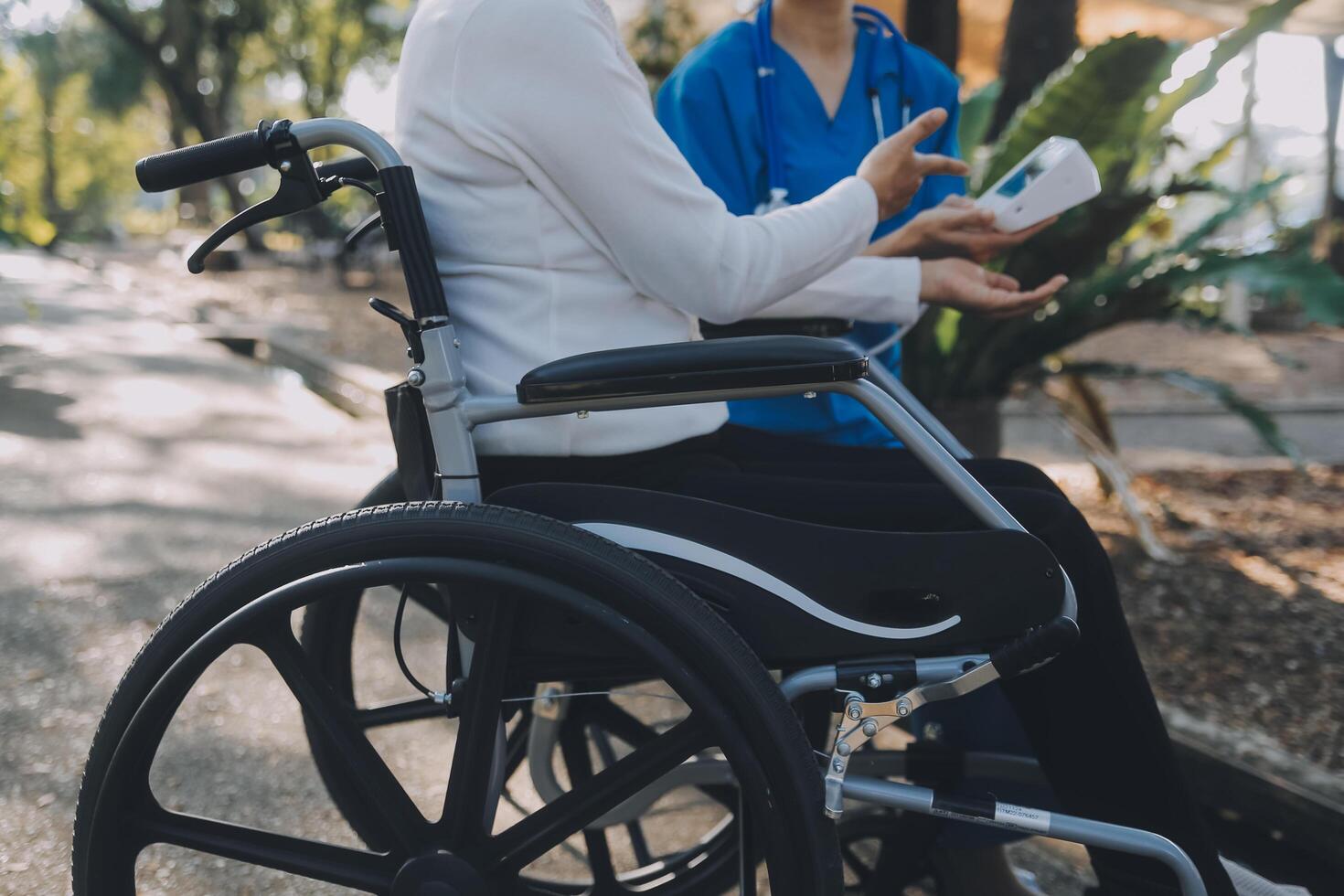 nurse with elderly man in wheelchair at park photo