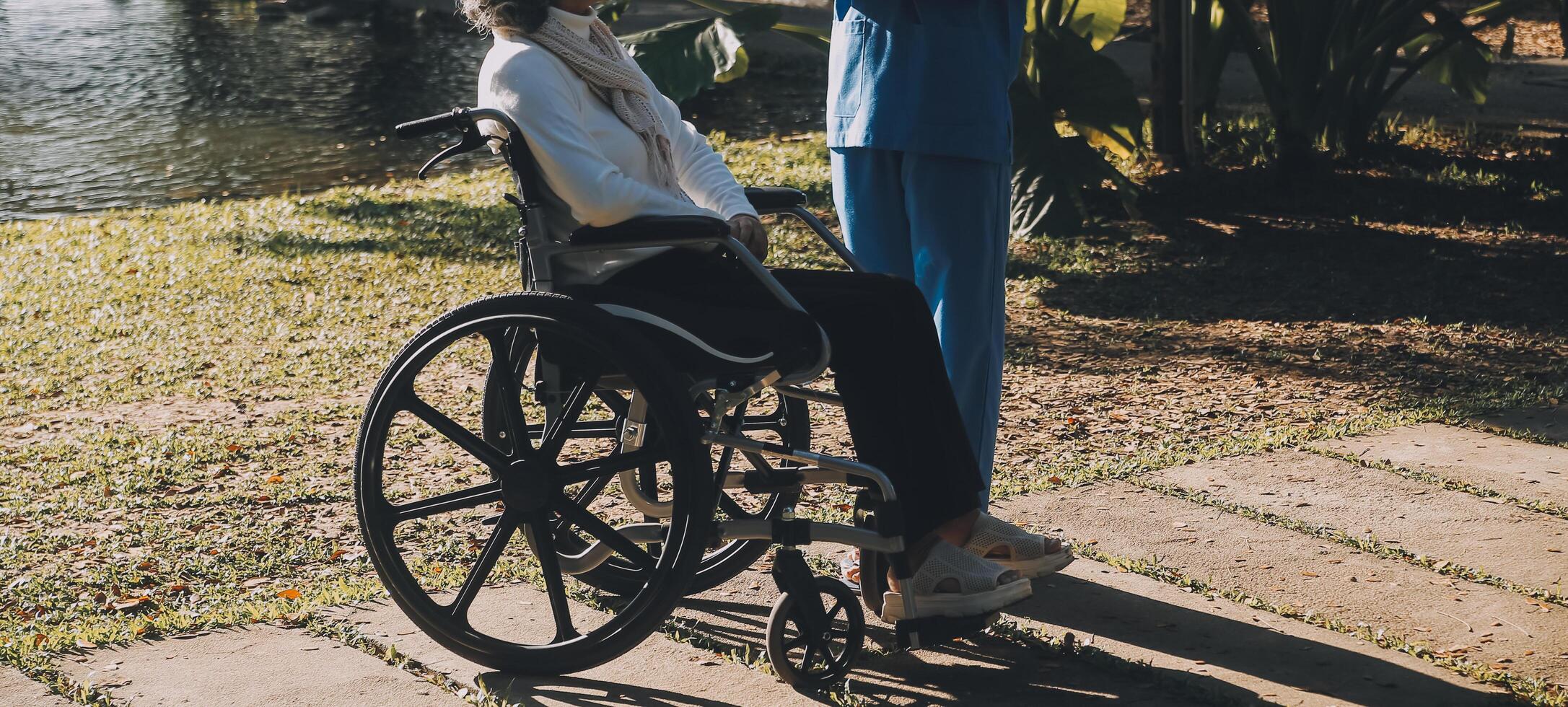 enfermería personal hablando a un mayor persona sentado en un silla de ruedas. foto